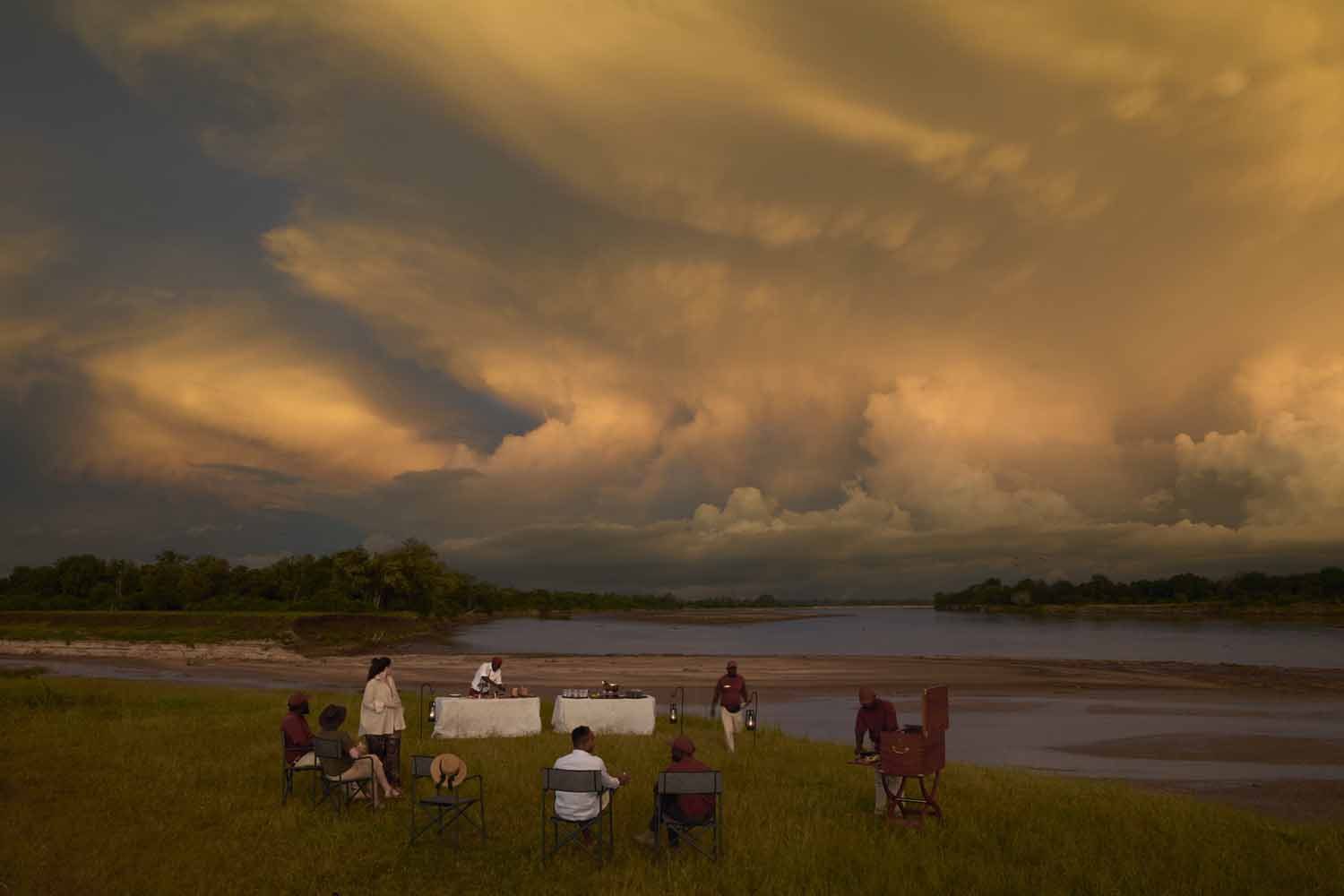 Sundowners on the banks of the Luangwa River under a storm-lit sky